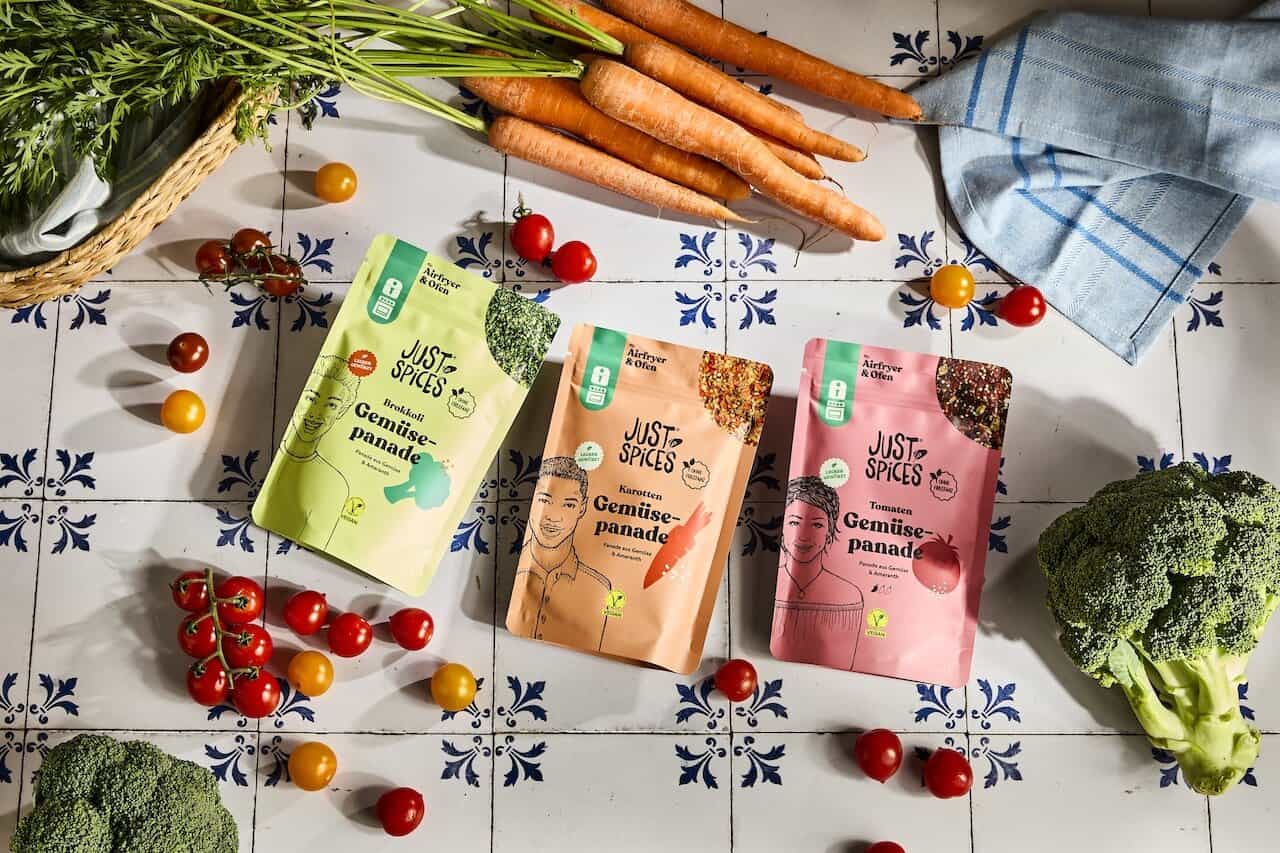Drei neue gemüse-panaden von just spices auf fliesentisch neben gemüse