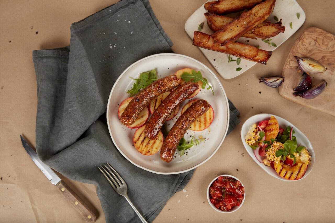 cultivated sausages from Ivy Farm on a plate with side dishes